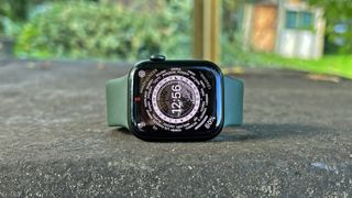 Apple Watch 7 med grøn rem liggende på siden