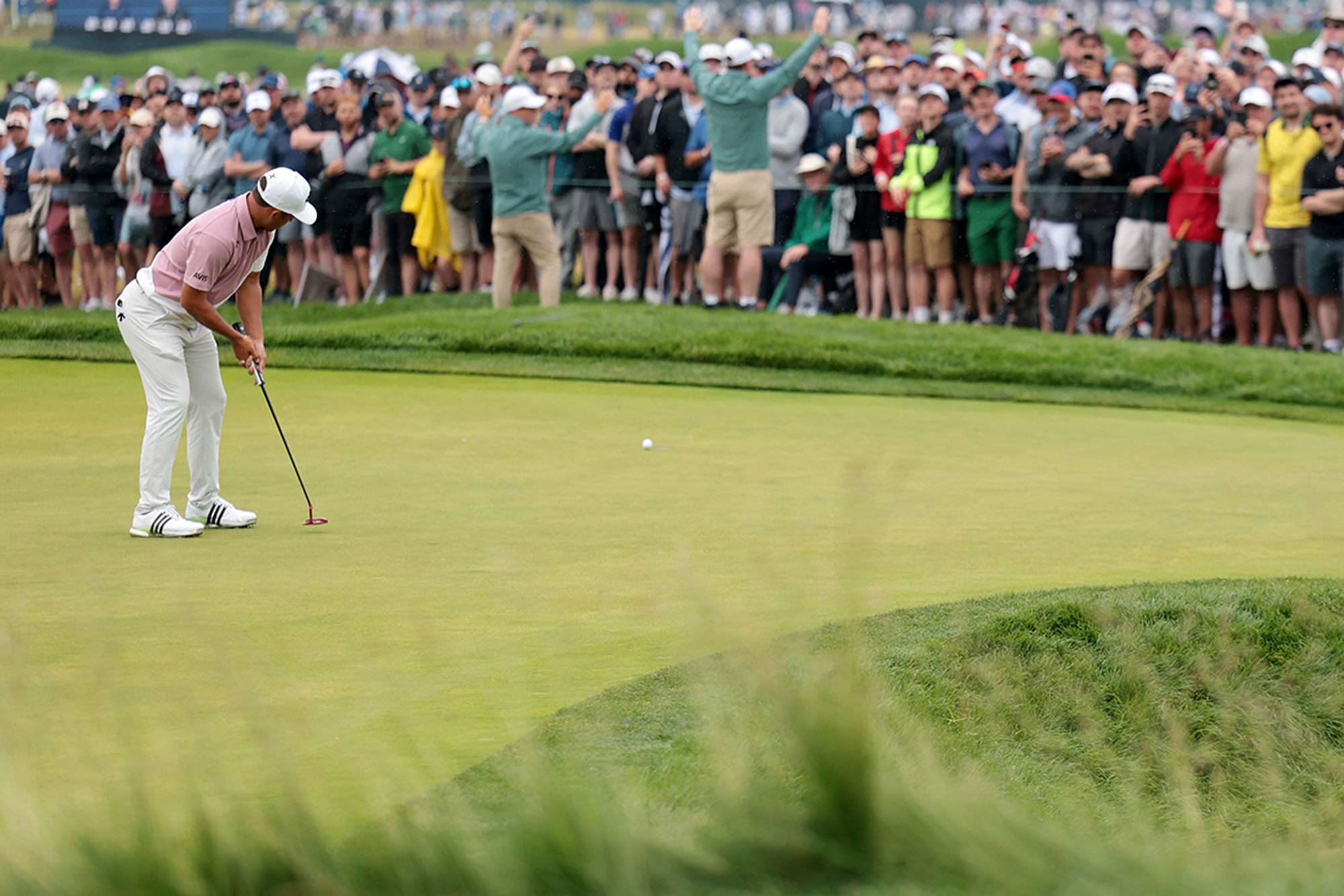 Xander Schauffele watching his putt at the US Open, as it rolls down the hill towards the hole