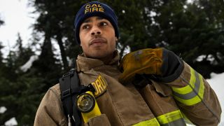 Jordan Calloway as Jake standing in the snow holding up his right hand to his right shoulder. 