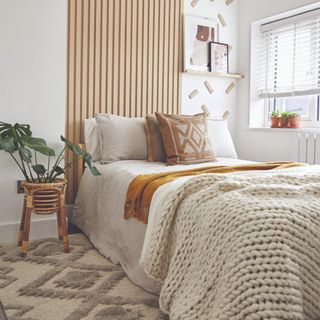 Bedroom with wooden wall paneling and a knitted throw on bed