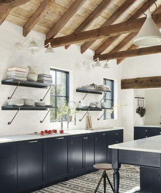 Modern farmhouse kitchen with dark blue cabinets, white walls and exposed wooden beams