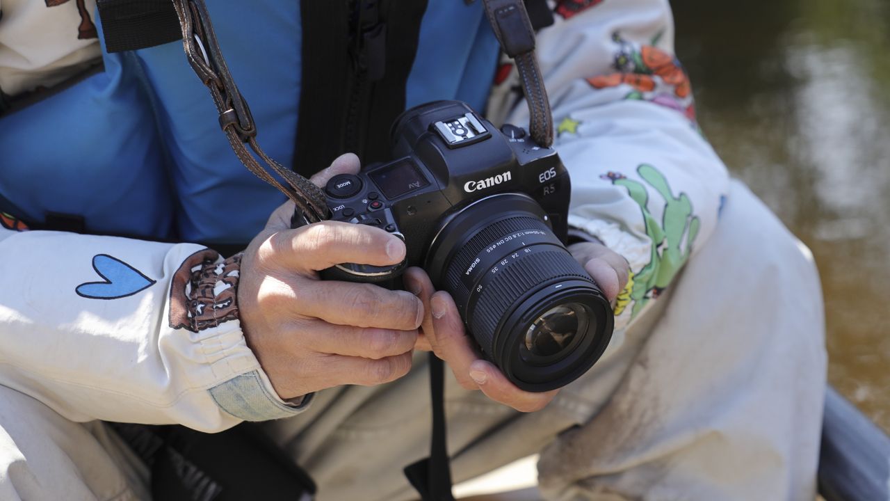 Sigma 18-50mm f/2.8 DC DN Contemporary lens in the hand, attached to a Canon EOS R5 camera