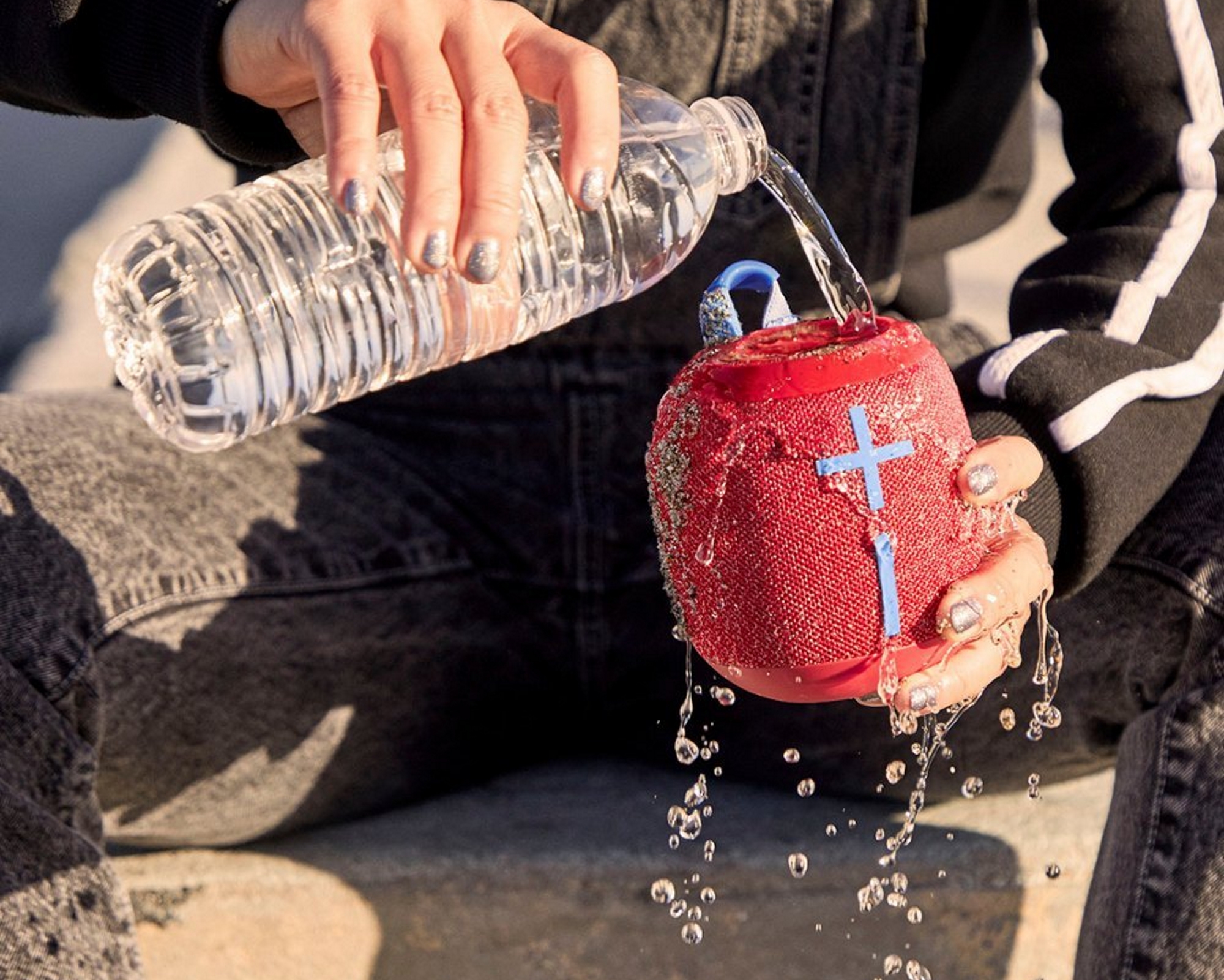 man pouring bottled water on the Ultimate Ears WONDERBOOM 2 shower speaker in red