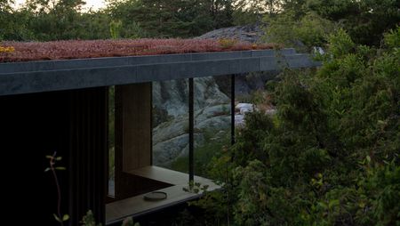 Cabin Lillesand a norwegian summer house with a green roof and glazed corner looking out to green nature