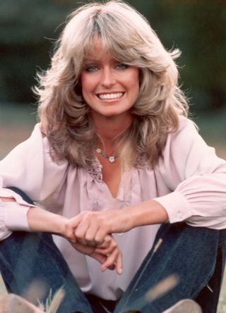 Farrah Fawcett in a meadow wearing pink blouse and jeans