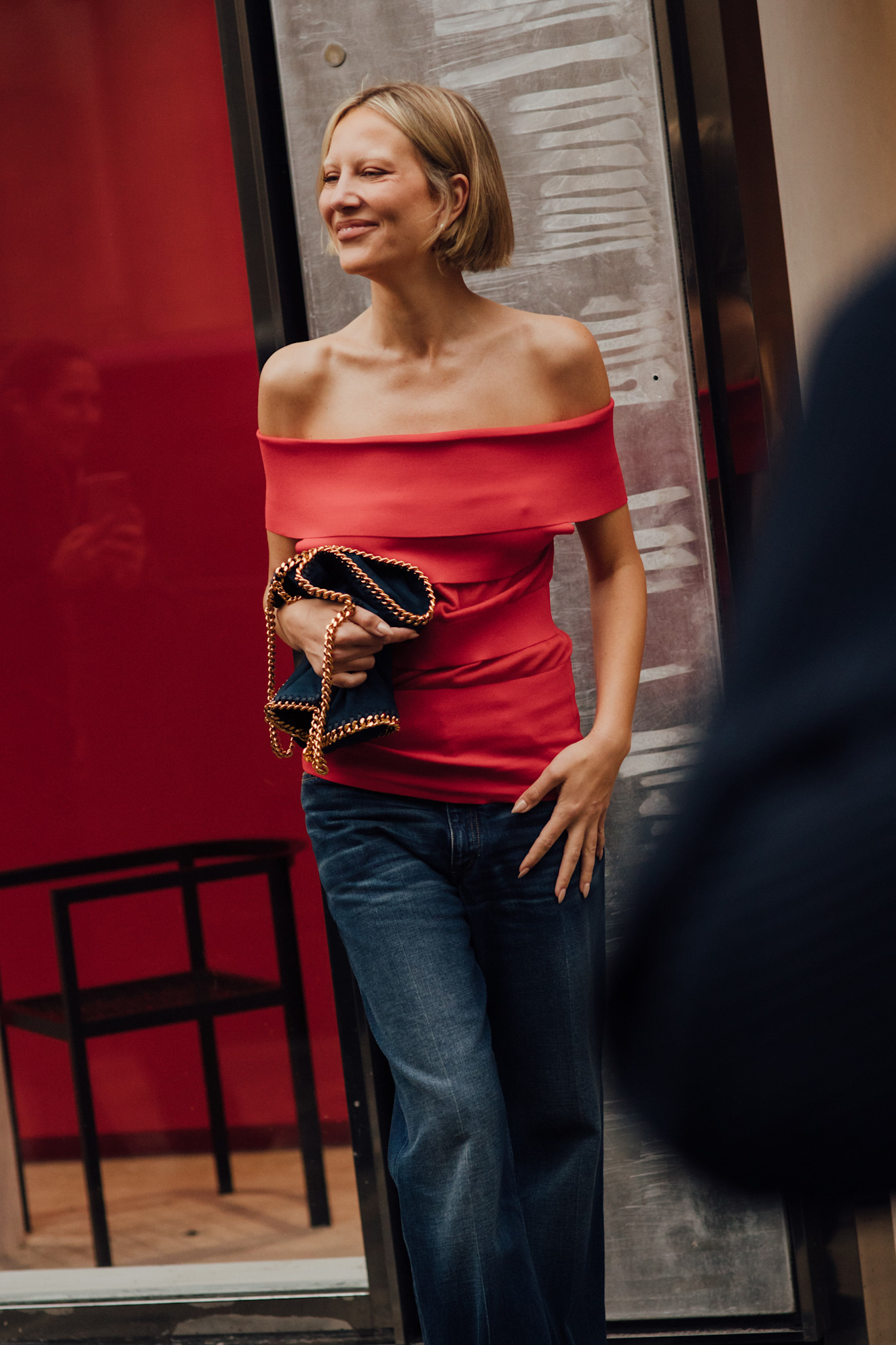 Paris Fashion Week attendee wears blue jeans with a red top.