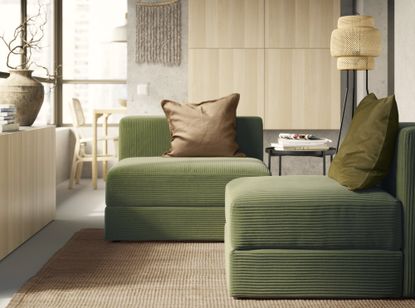 A living room with dark green textured chairs, a natural woven rug, and wooden shelving on the walls