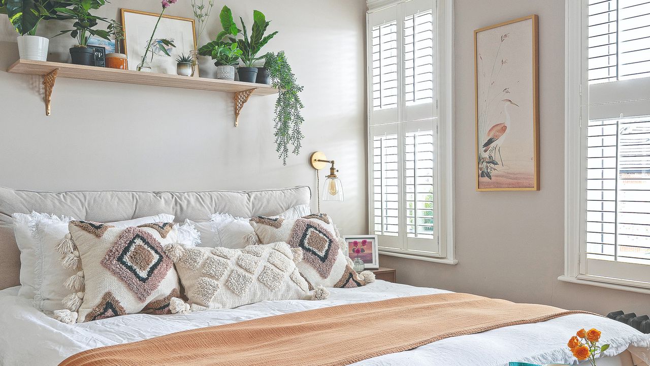 Grey wall with mounted light and white bedding