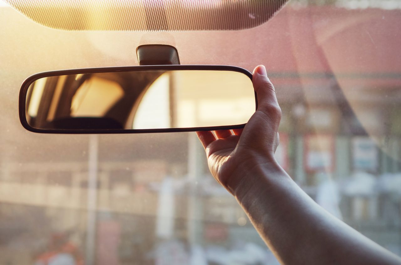 A driver adjusting the rear view mirror. 