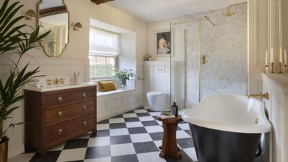 A bathroom with black and white chequered floor tiles, a large tub, a wooden vanity, and a walk-in shower