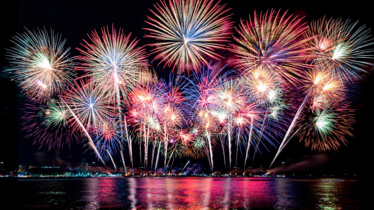 Fireworks light up the sky over a lake.