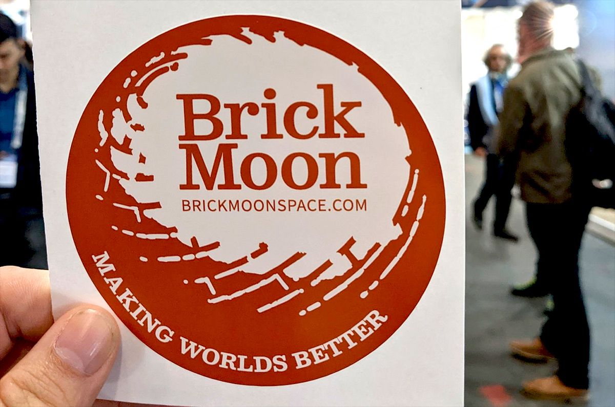 Space archaeologist Justin Walsh, co-founder of Brick Moon, holds up a decal with the new space habitat consultancy&#039;s logo at the International Astronautical Congress (IAC) in Paris, France.