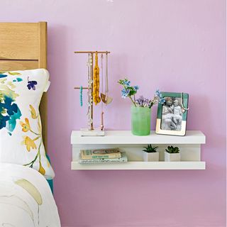 pink painted bedroom with white bedside shelf