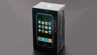 An unopened original iPhone in a box on a black table
