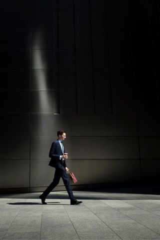 Photograph of an office worker walking in a shaft of sunlight. Photographed by Sean Tucker