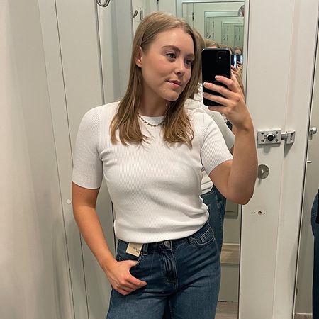 Woman in dressing room wears white top and blue jeans