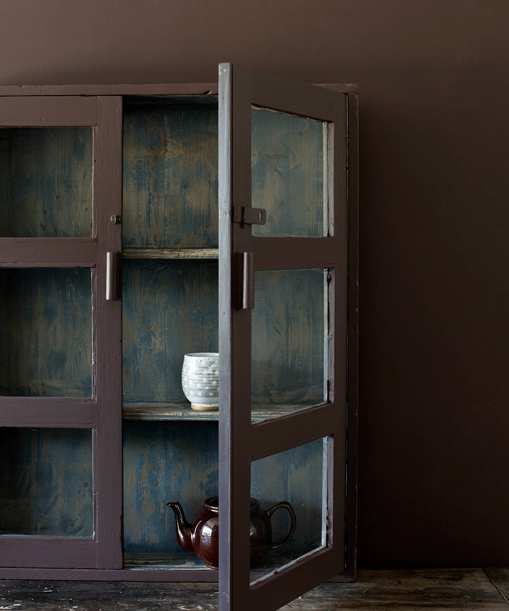 A brown painted dresser with door open