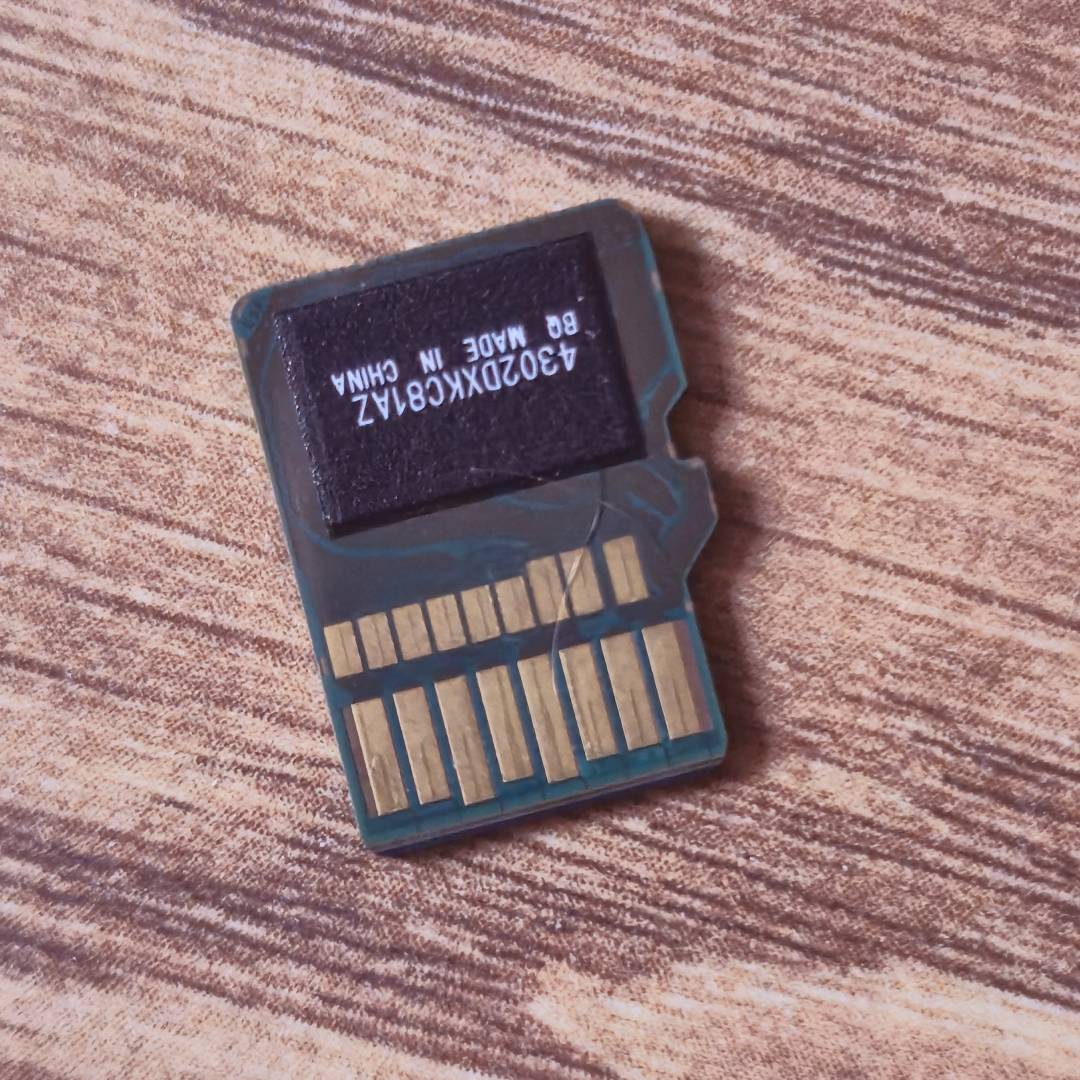 MicroSD Express card with contacts facing upwards on woodgrain desk.