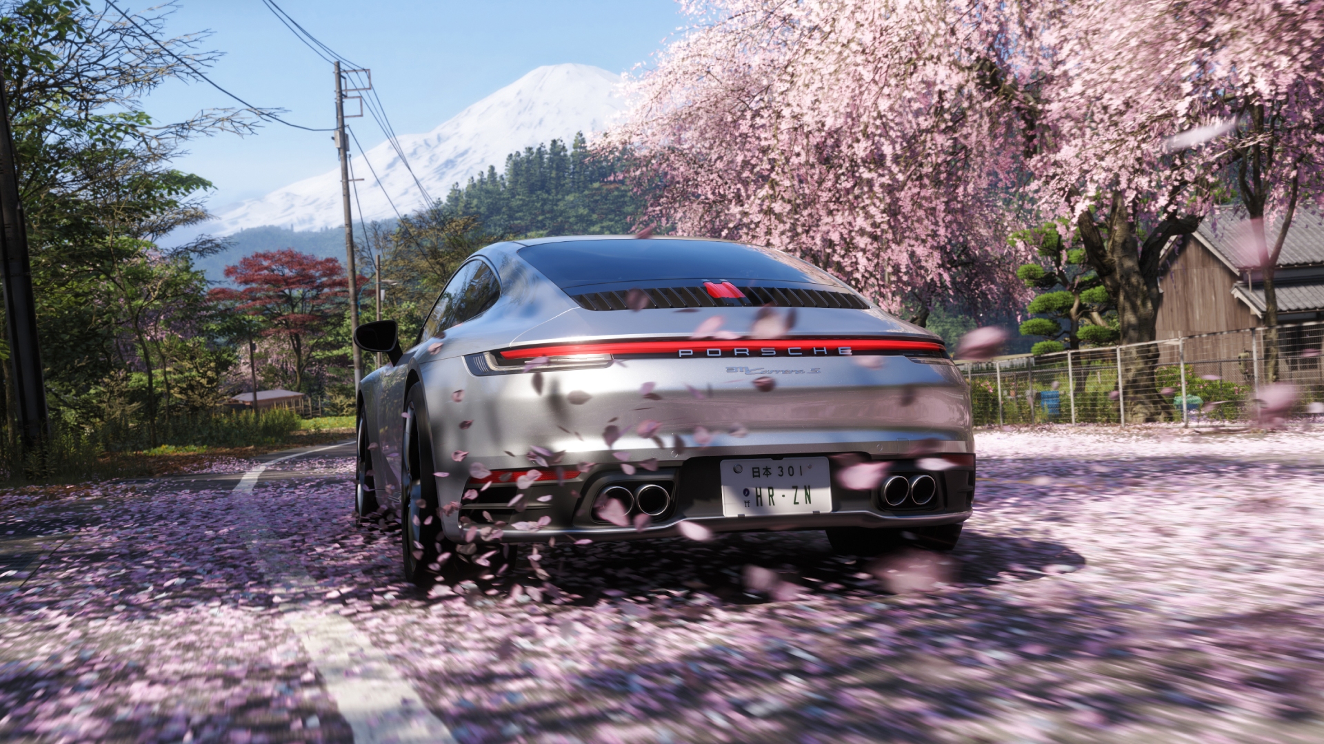 A silver Porsche races down a road covered in cherry blossom petals in Forza Horizon 6.