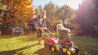 Mum and daughter mowing grass in autumn