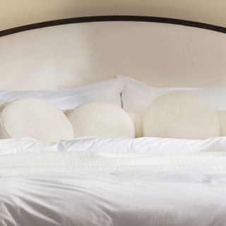 Lecco Cashmere Round Pillows on a bed.