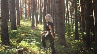 a woman walking through a forest 