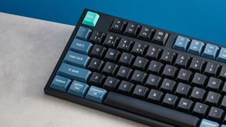 Keychron B36 keyboard and Keychron BM25 mouse photographed in front of a blue background. 