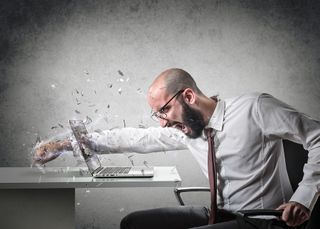 Angry businessman punches through his laptop screen