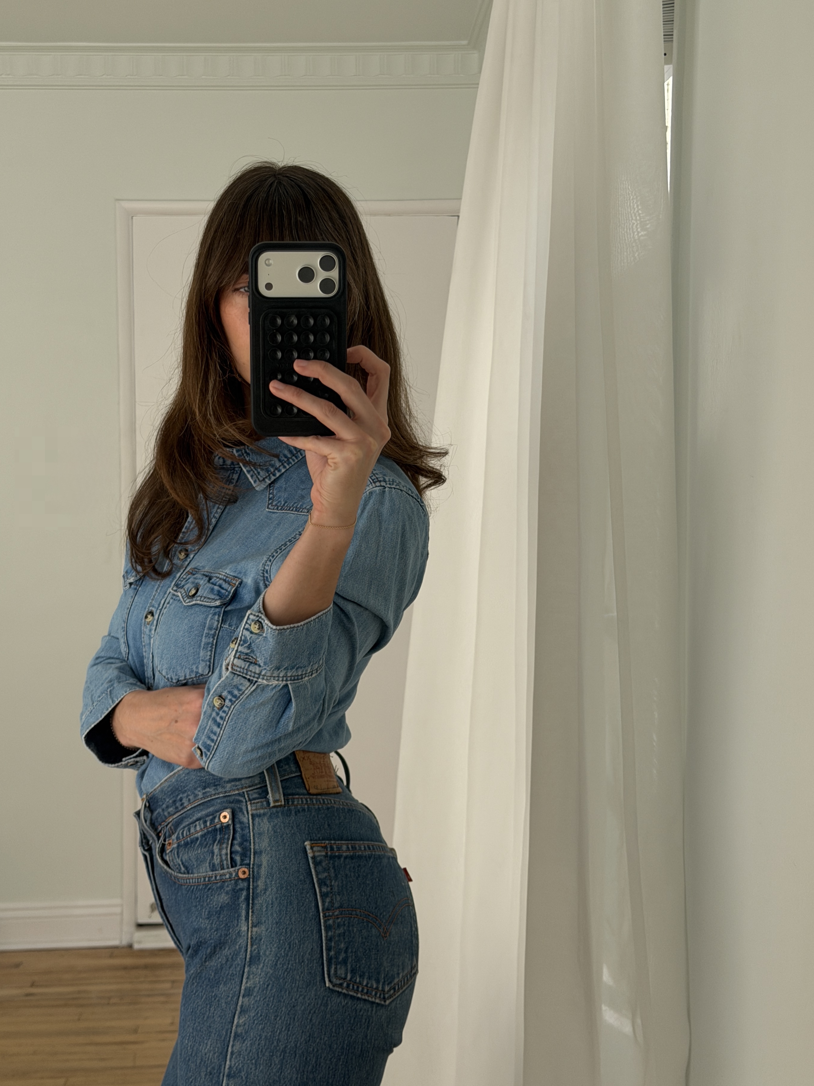 Kathryn Zahorak posing in mirror wearing denim shirt and jeans and leopard print heels 