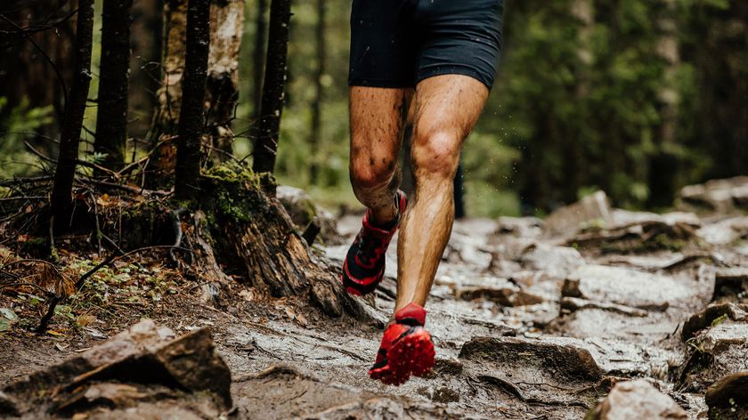 A man wearing trail running shoes running on a rocky path