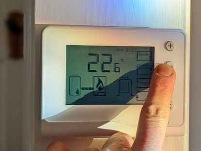Person turning down the central heating with a wireless thermostat