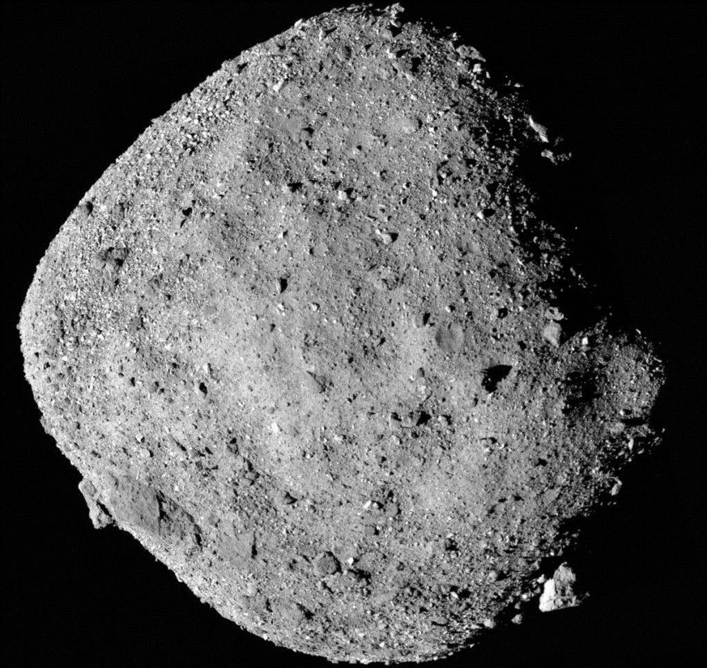 A close up of a gray rocky asteroid in the darkness of space