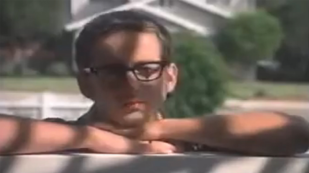 A kid with glasses looking over a fence in Eight Days A Week.