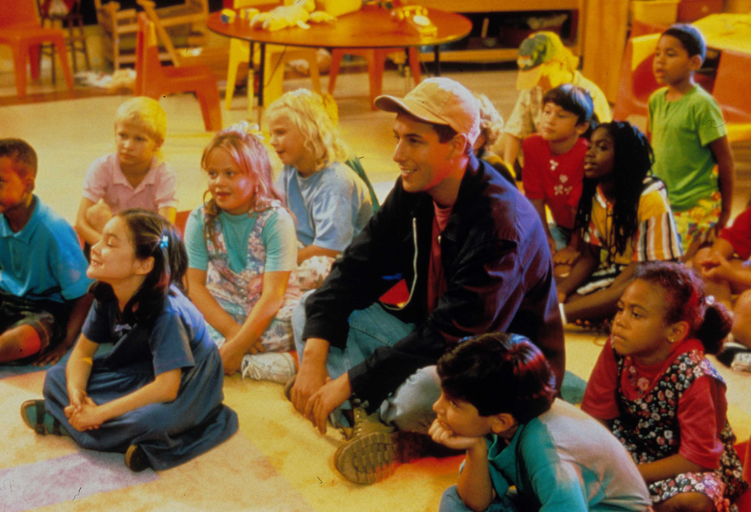 Adam Sandler stars in 'Billy Madison' as an adult man in a baseball hat sitting in a kindergarten classroom