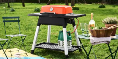 Orange Everdure Force BBQ in garden with chairs and table 