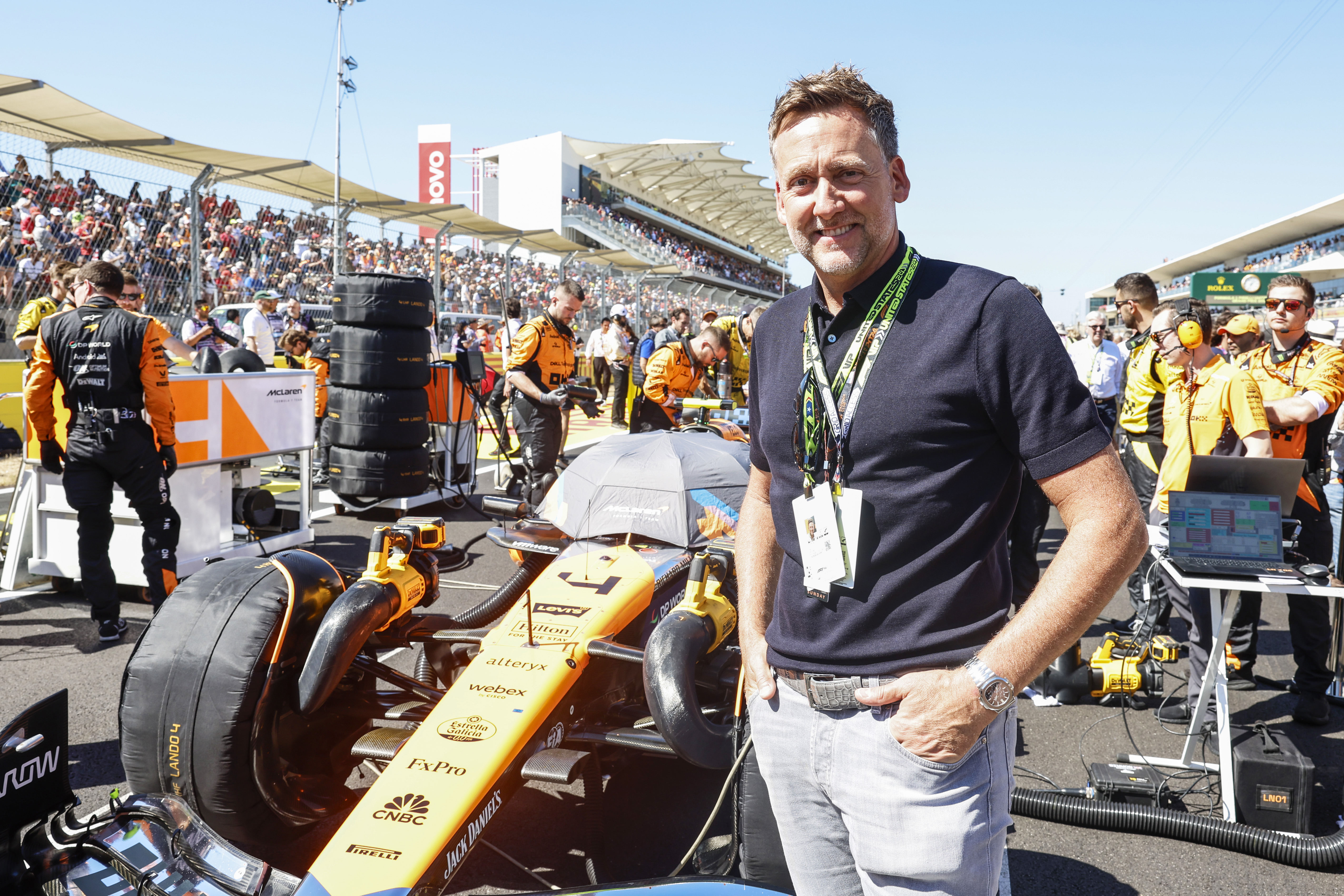 Golfer Ian Poulter poses in front of the car of Lando Norris, McLaren MCL38, on the grid during the F1 Grand Prix of United States at Circuit of The Americas