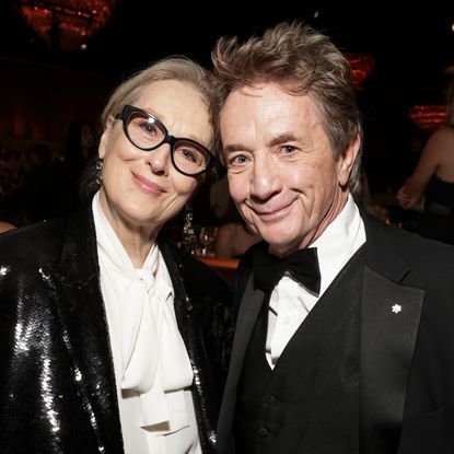 Meryl Streep wears a white pussy bow blouse and a black sequin jacket while she poses with Martin Short, who is wearing a tuxedo