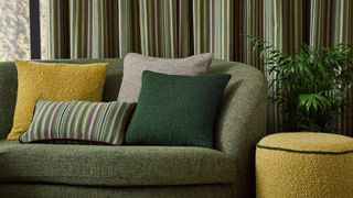 green boucle sofa with green and yellow cushions, in front of green curtains