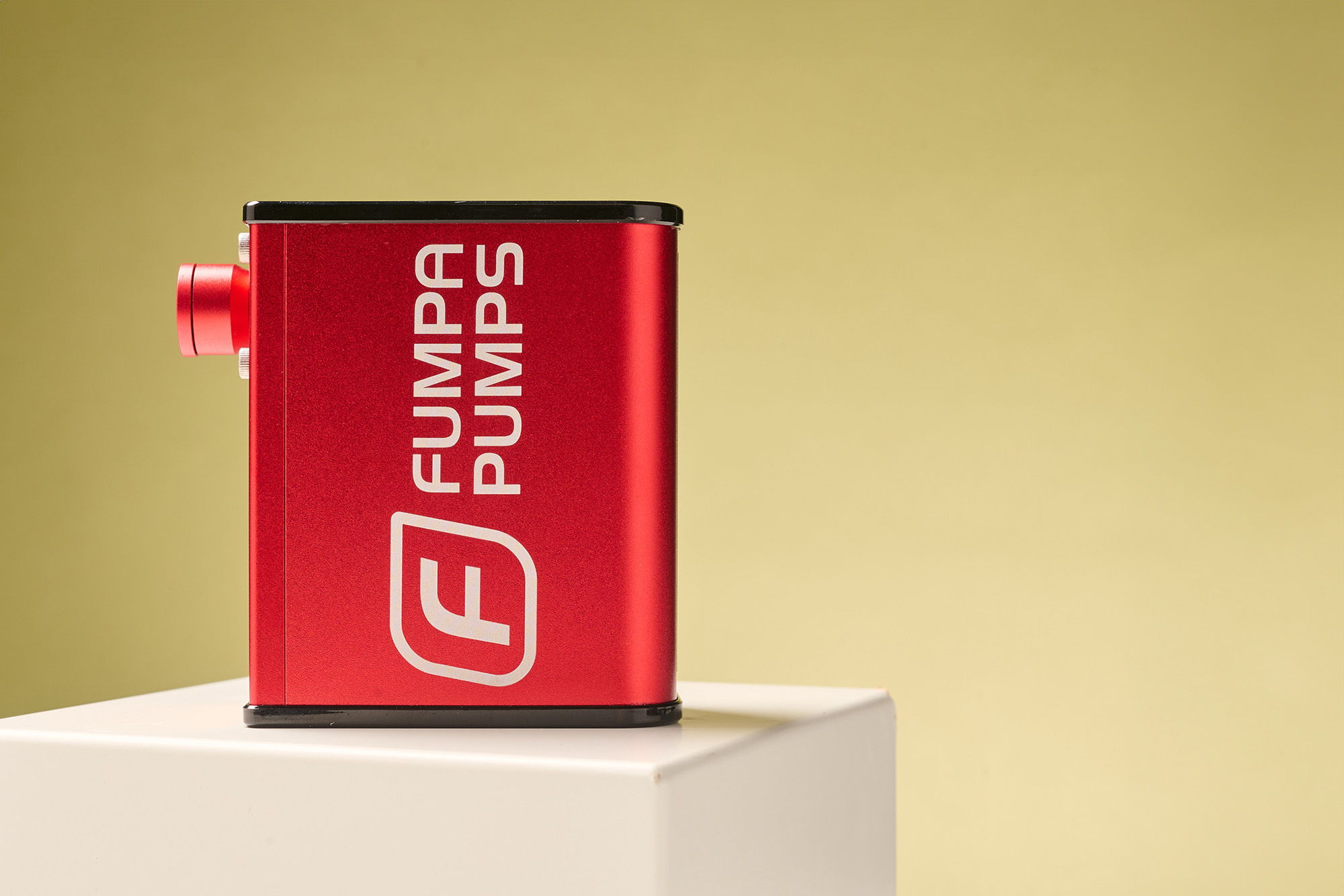The clean-cut red Fumpa Nano pump, sat against a mustard yellow background.