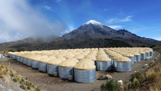 Hundreds of covered tanks in front of a mountain