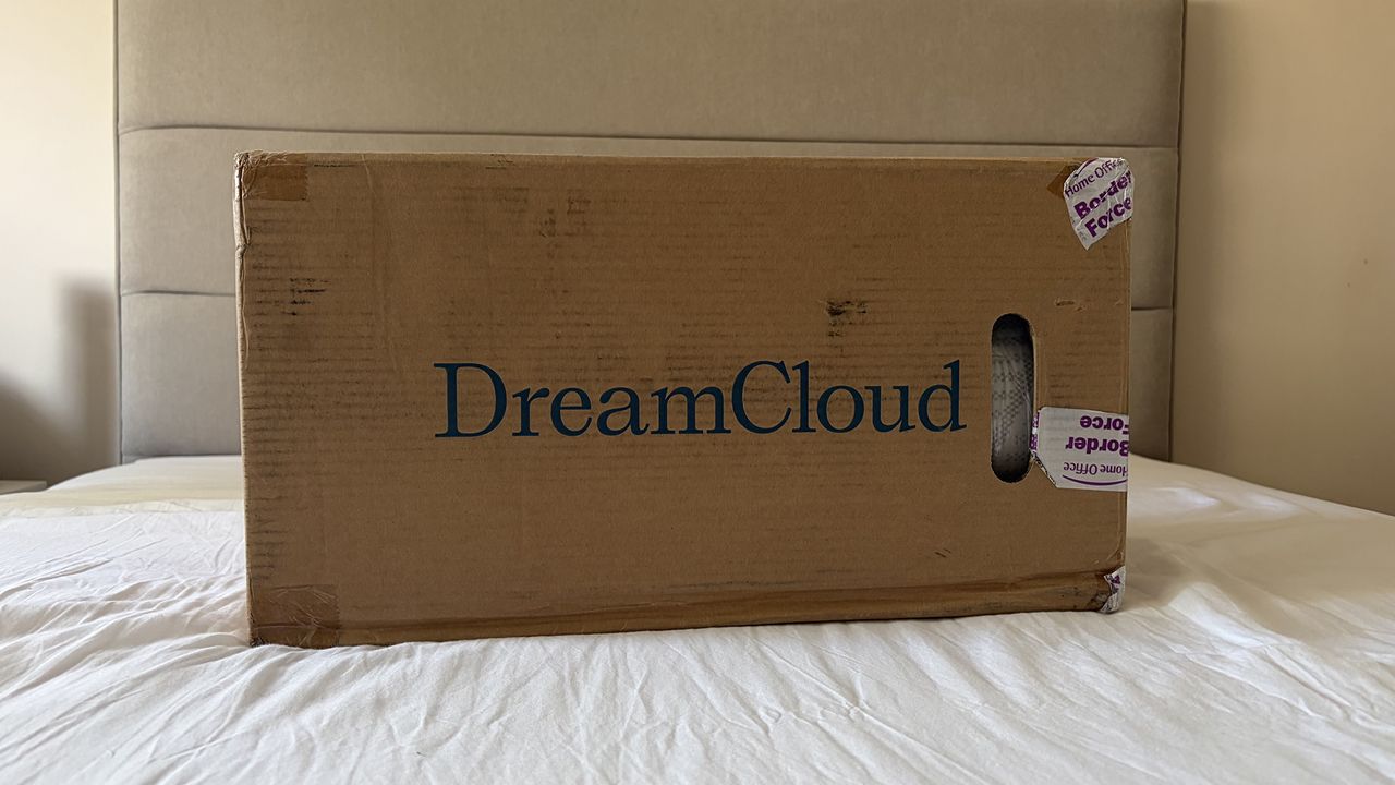 A cardboard box saying DreamCloud on a bed in the room of our mattress tester Ruth Jones