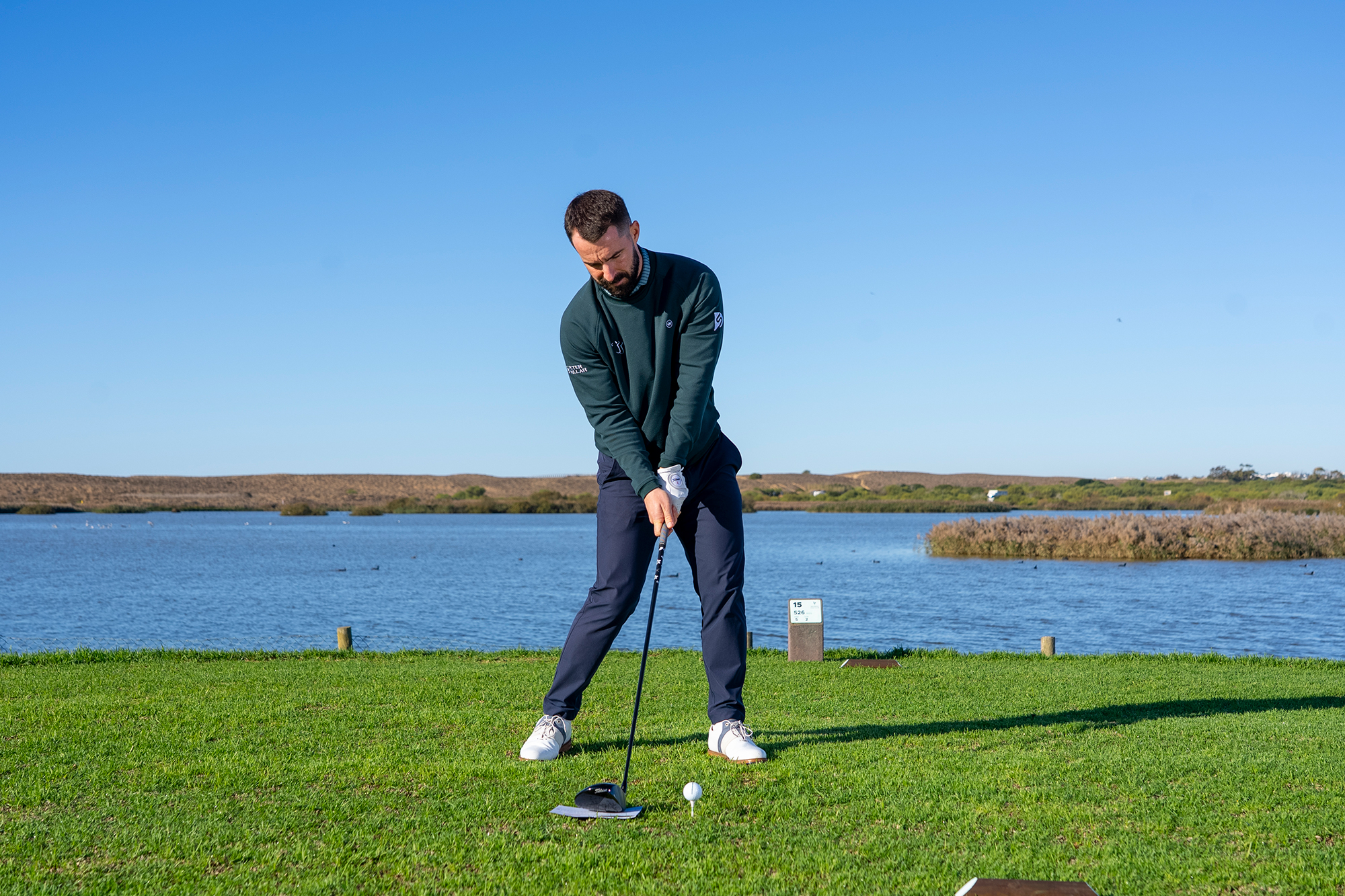 Top 50 Coach James Jankowksi demonstrating a drill that amateurs can use to improve their driver launch angle using a scorecard placed behind the golf ball (that is sitting on a tee), with James also demonstrating the attack angle at impact
