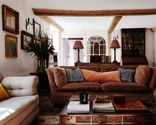 farmhouse living room with brown sofa, rugs on flagstone floor and feature window