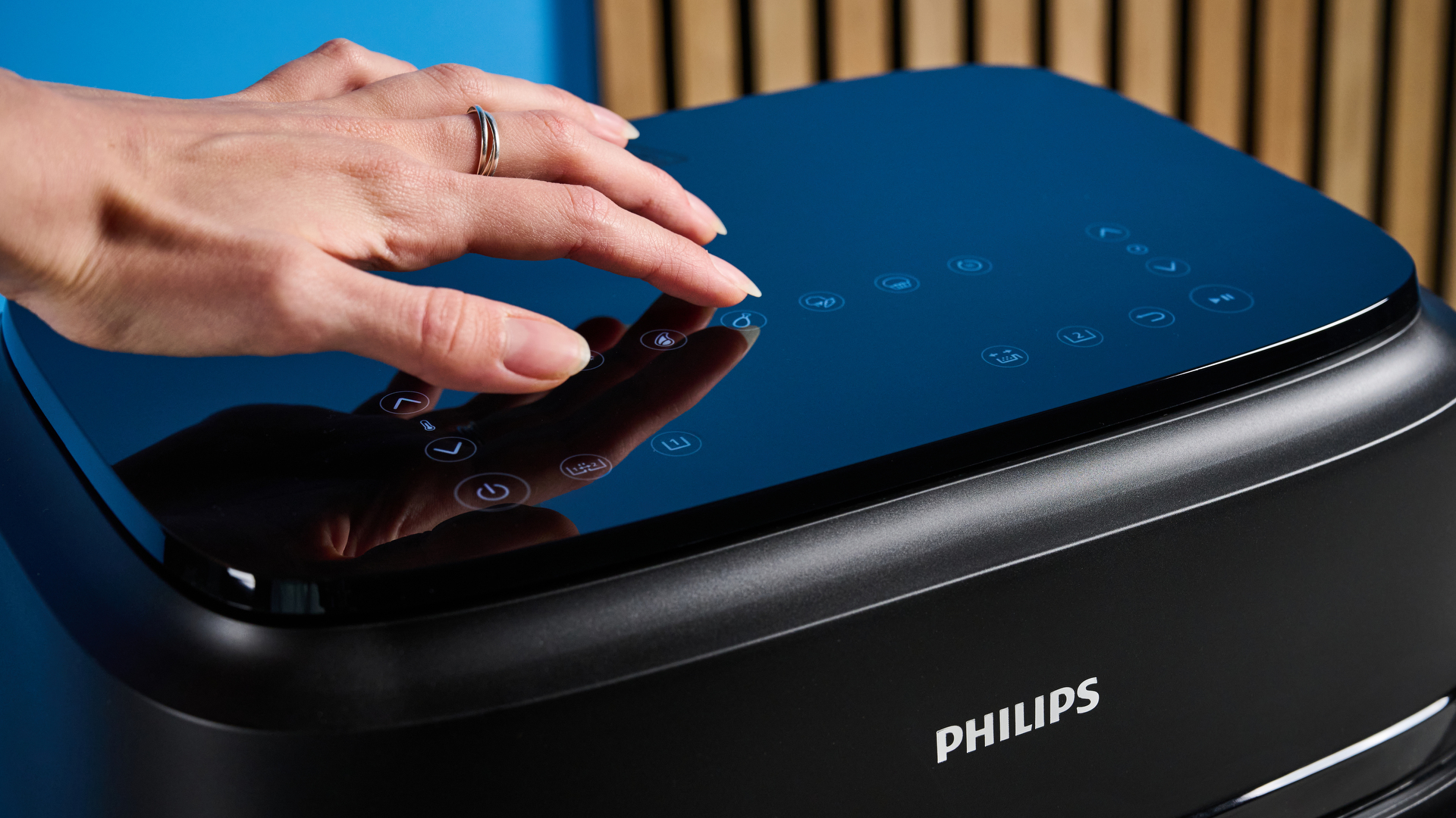 The touch controls of the Philips 1000 Series FlexDrawer Air Fryer photographed in front of a blue background.