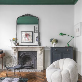 white and green living room, green painted ceiling, green lamp, large vintage mirror on marble mantel, retro wire chair, boucle armchair, herringbone flooring