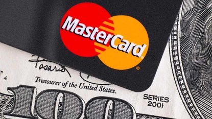 A Mastercard card sitting on a 100-dollar bill