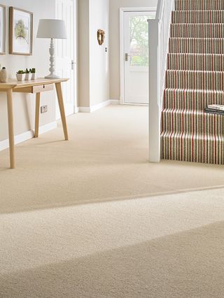 hallway with cream carpets and striped stair runner