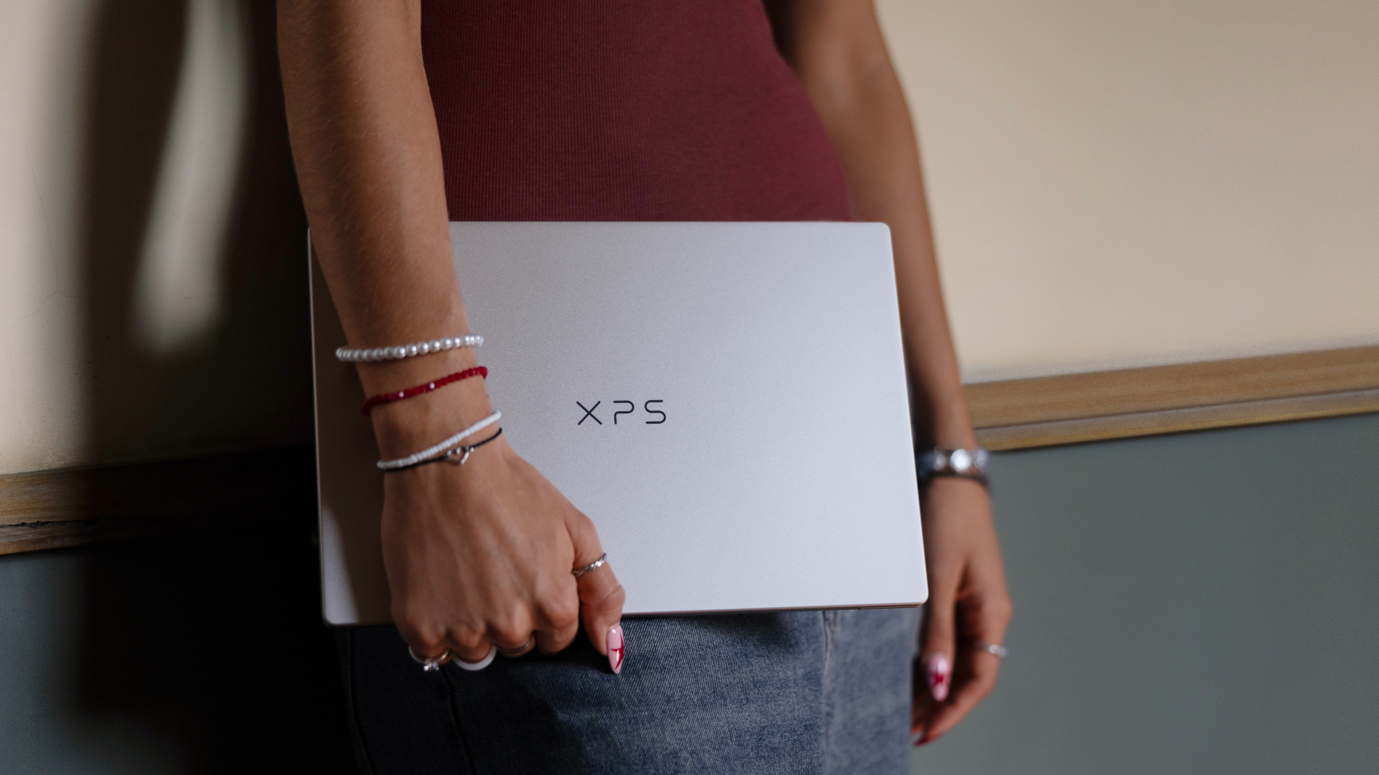 Dell XPS 13 laptop closed, being held by someone leaning back against a wall