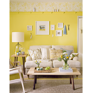 living area with yellow wall and sofa with cushions and wooden floor