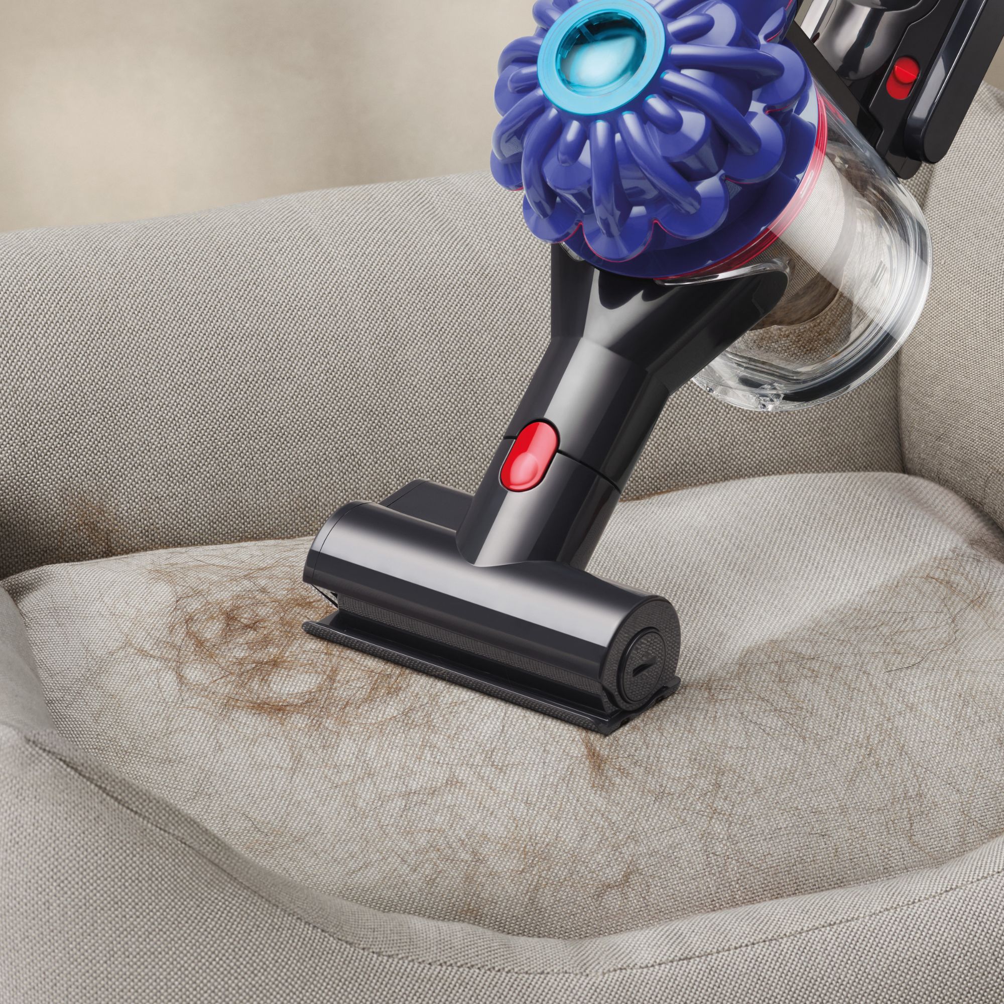 Dyson V10 Konical in handheld vacuum mode, vacuuming pet hair from a grey dog bed